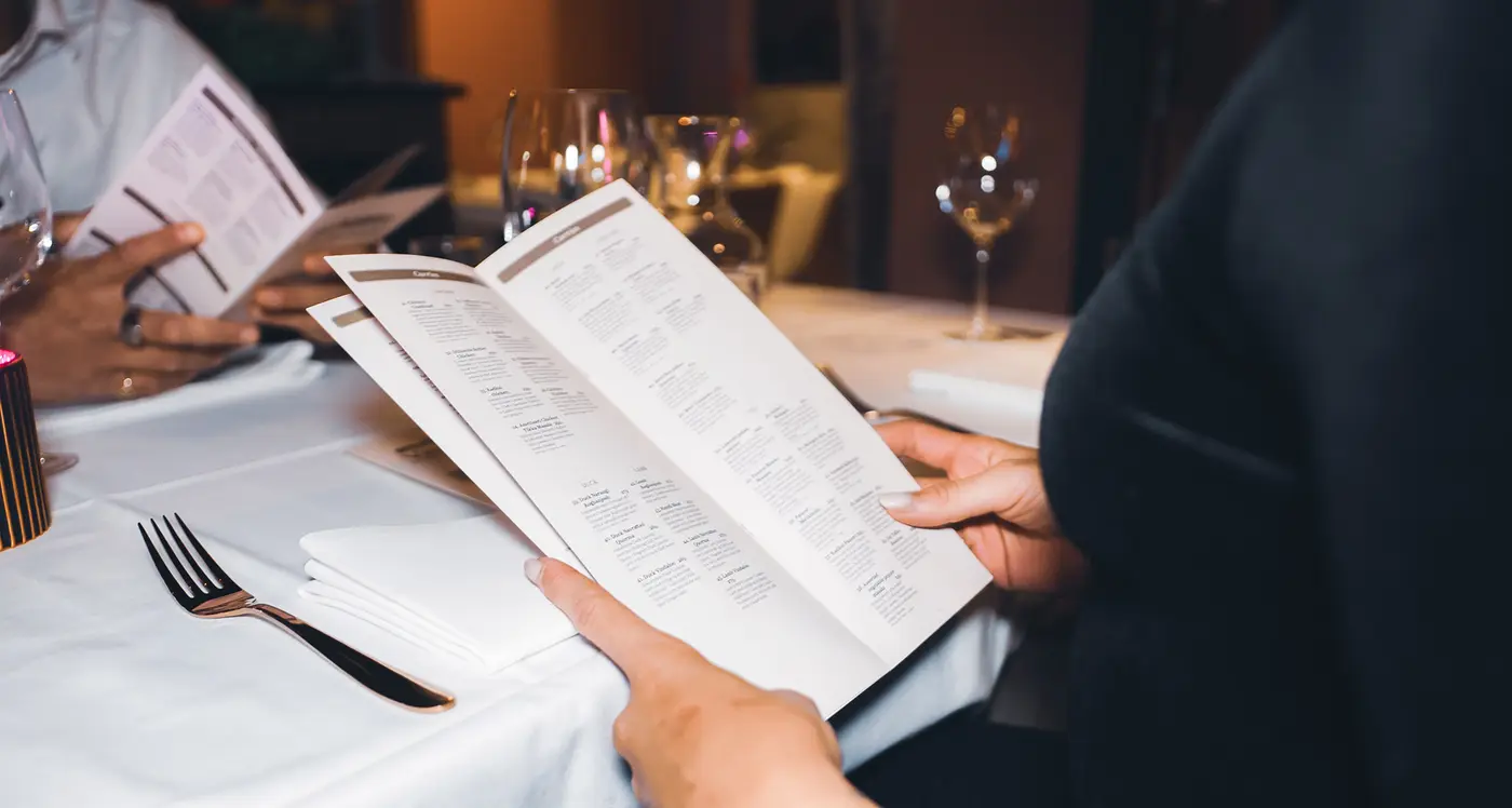 Gjester som studerer menyen ved et dekket bord i restauranten
